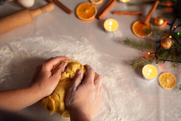 Girl's hands kneading dough on the table with white tablecloth. Christmas baking, preparing for winter holidays concept.