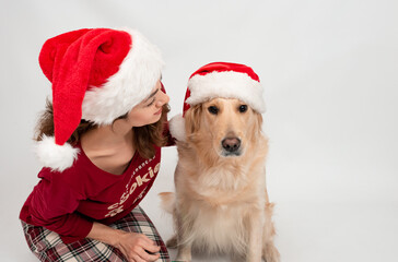 Curly girl in Santa Claus hat with dog labrador retriever waiting for the New Year. Celebrating Christmas or New Year eve, pajama party.