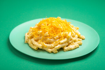 Mac and cheese on a plate isolated on a green background.