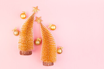 Golden christmas decorations with christmas trees, stars, balls on soft light pink background, copy space, top view.