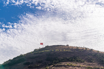 Fototapeta na wymiar Turkish flag over the hill. with beautiful white clouds and blue sky