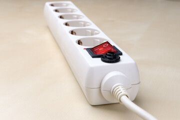 The socket with a button for six plugs lies on a light surface.