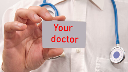 Your doctor lettering text on a business card in the hands of a doctor close-up..