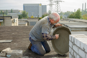 Man is using up mortar’s leftover for repairing of roof.