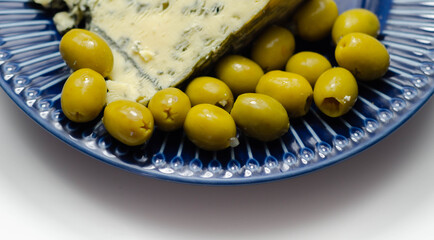 Pickled olives stuffed garlic with full fat soft blue veined cheese on the blue plate