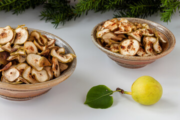 Dried healthy homemade fruit snacks in two bowls: one with spices and another without. Asian Pear dehydration, whole fruit in front.