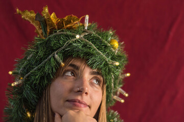 Young beautiful woman with a christmas wreath in the head in red background