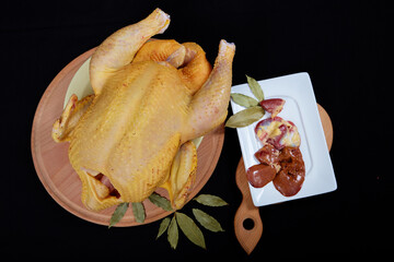 Raw chicken on black background. © Malsveta