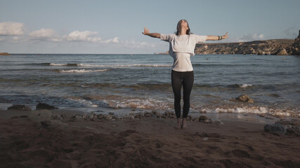 Young caucasian brunette woman doing youga on the sandy beach in the morning. High quality photo