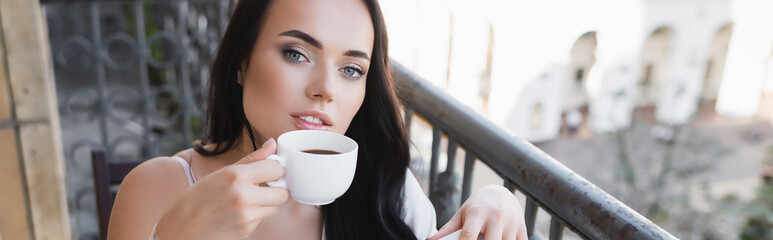 beautiful brunette woman drinking coffee on balcony, horizontal banner