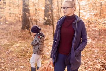 Obraz premium Woman with son in the autumn forest on a walk. Girl in the woods.
