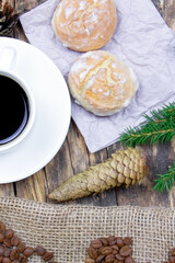 A white cup of coffee and cakes on a wooden background. Coffee beens on a linen fabric. Breakfast coffee. Fir branch