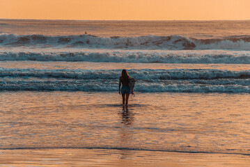Fototapeta na wymiar Female surfer on the beach at the sunset in Balneario Comboriu state of Santa Catarina