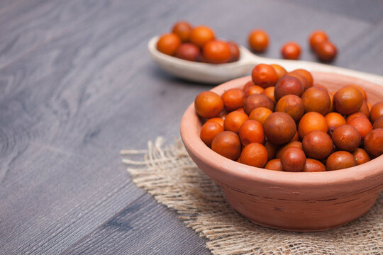 A clay plate with fresh ziziphus on wooden background.