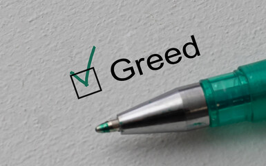 Greed - checkbox with a tick on white paper with pen. Checklist concept.