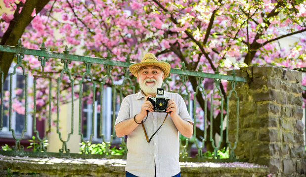 Walking his favorite street. Travel and tourism. Travel photo. Photographer in blooming garden. Capturing beauty. Senior man hold camera. Retirement travel. Spring holidays. Enjoying free time