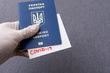 Hand in medical glove holding passport with Covid-19 note. Coronavirus disease outbreak. Travelling...