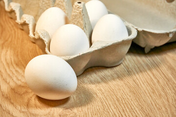 Raw chicken eggs in a cardboard box on the table.