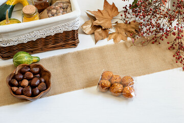 Pumpkins, spices, chestnuts and panelles de piñones prepared for packing in gift basket. Halloween festive emotions, autumn rustic background.