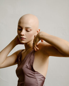 Portrait of a young bald girl in a tender dress. Minimalist studio portrait
