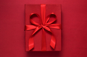 Red gift box on red background with red ribbon - greeting concept