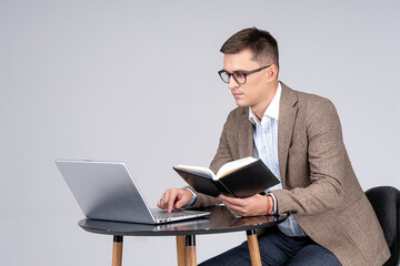 Male sales manager cheking schedule in notepad. Laptop on desk. Professional at work.