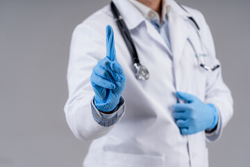 Selective focus on doctor`s hands in blue medical gloves. Cropped photo of a medic in scrubs. Healthcare concept.