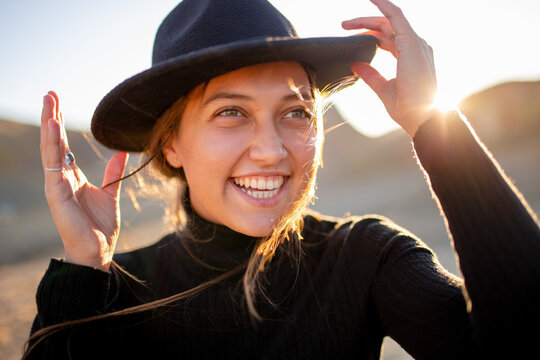 beautiful portrait in the sunshine of a young laughing girl in a felt hat