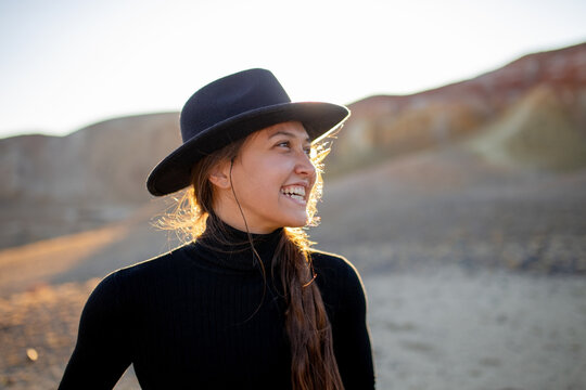 beautiful portrait in the sunshine of a young laughing girl in a felt hat