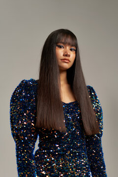Serious long haired woman in shiny dress looking at camera