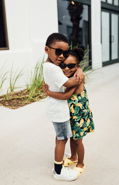 Brother and Sister in matching outfits hugging and holding hands