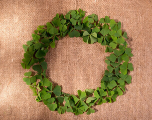 Happy Saint Patrick's Day background with a round frame made of green fresh shamrock leaves on a...