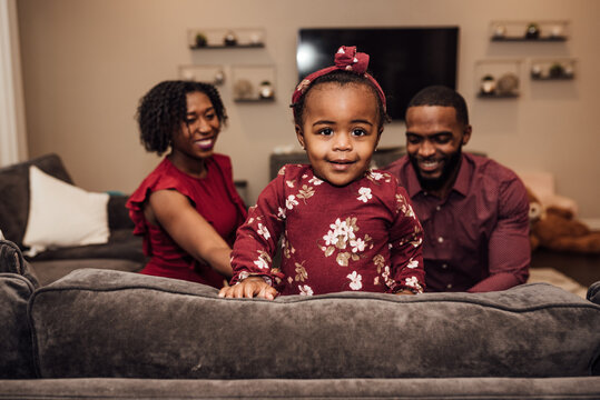Toddler smiling while parents watch in the background