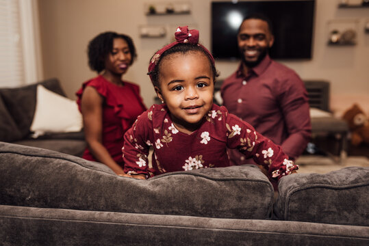 Toddler smiling while parents watch in the background