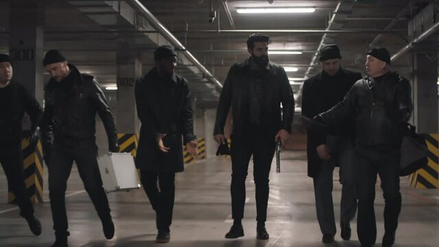 Front-view full footage of multi ethnic bandits fleeing scene of crime constantly looking around in fear of getting caught arguing with each other