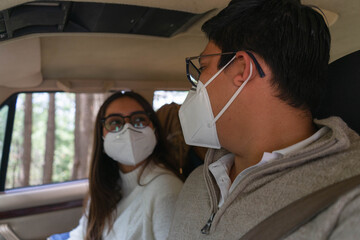 woman and man with masks talking in the car