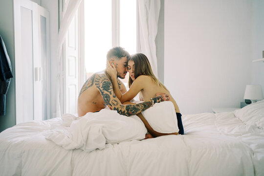 Tattooed man embracing semi naked girlfriend