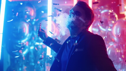 Relaxed guy smoking in nightclub. Man dancing with electronic cigarette at party