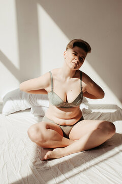 Woman taking off bra on bed