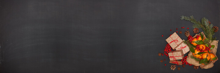 Festive background from fir branches, gift boxes, mandarins with leaves, spices. Extra wide panorama banner background.