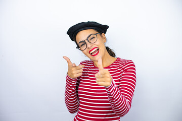 Young beautiful brunette woman wearing french beret and glasses over white background pointing to you and the camera with fingers, smiling positive and cheerful