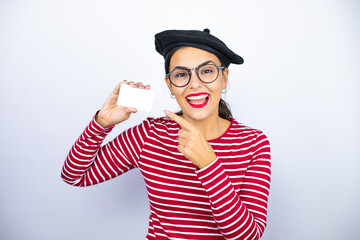 Young beautiful brunette woman wearing french beret and glasses over white background smiling and holding white card