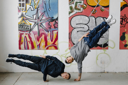 Dancers making tricks near graffiti wall.
