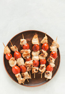 Chicken Skewers With Cherry Tomatoes On A Ceramic Plate On A White Background