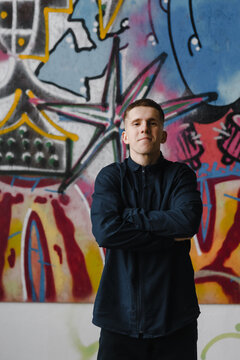Boy standing near graffiti wall.