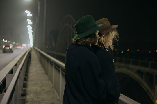 a couple in suits and hats stands on the bridge