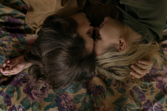 a family of three gays lies on the bed, a closeup photo of how the guys pressed their nose to nose close and smile