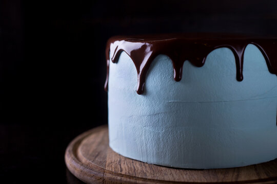 Blue souffle cake with chocolate icing on a dark wooden background