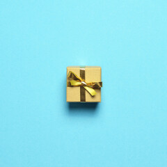 Christmas gift with golden ribbon on pastel blue background