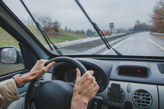hands of man on steering wheel driving car